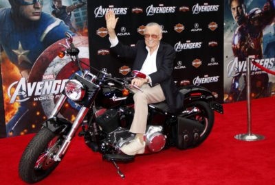 an older man sitting on a motorcycle in front of a poster
