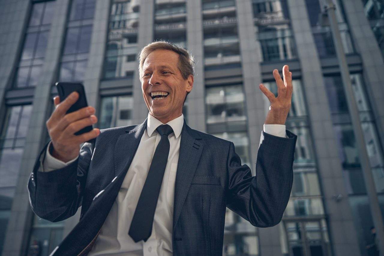 Happy businessman using smartphone on the street seo, web design & marketing agency