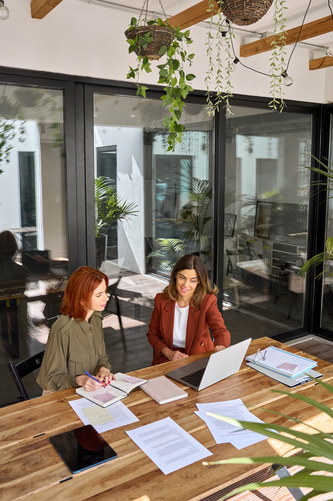 Two busy business women talking working at desk in green office. Top view.
