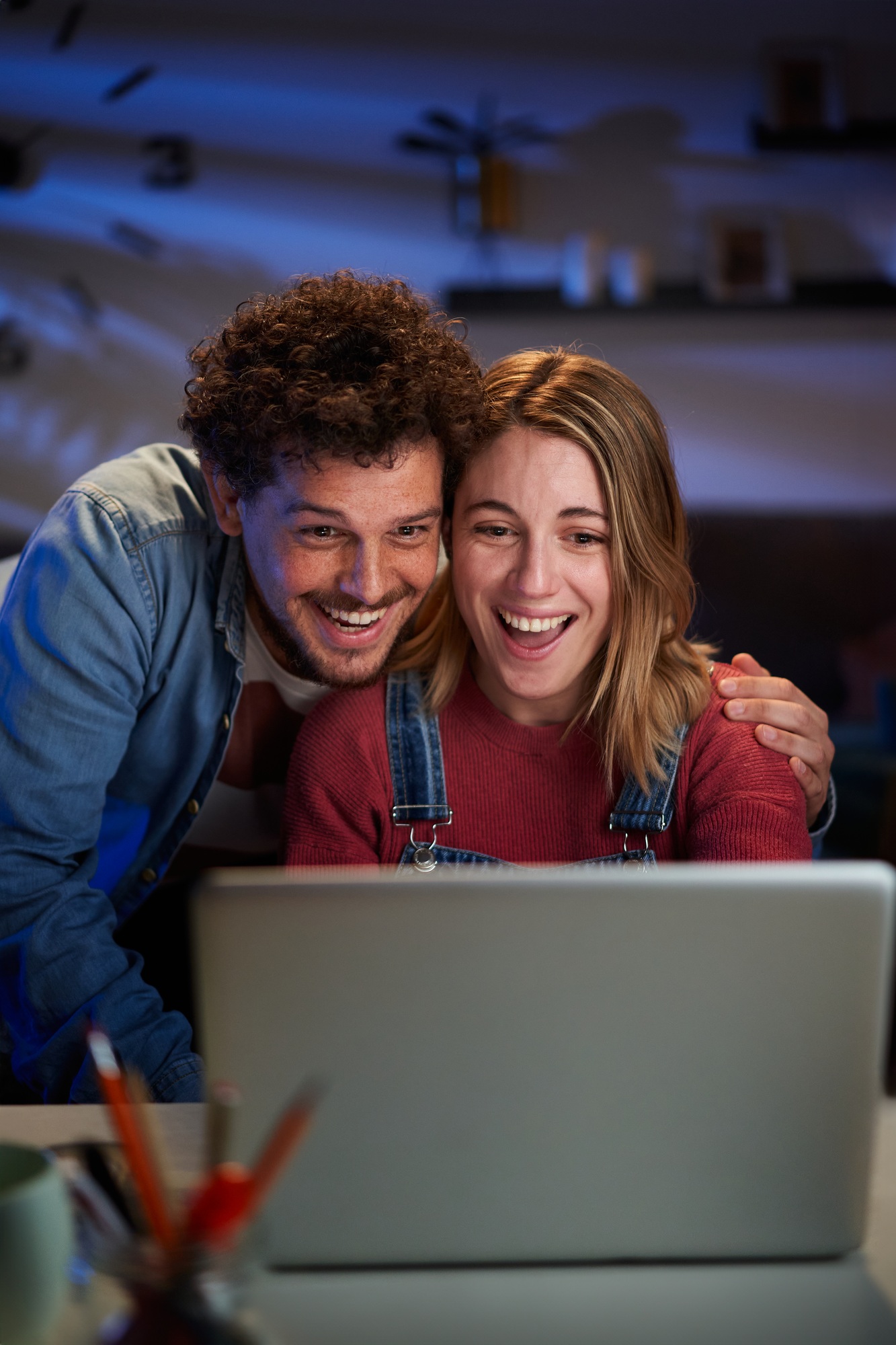 Vertical excited young adult caucasian couple looking at laptop surprised celebrating successful.