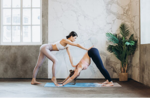 two women doing yoga poses in front of a window